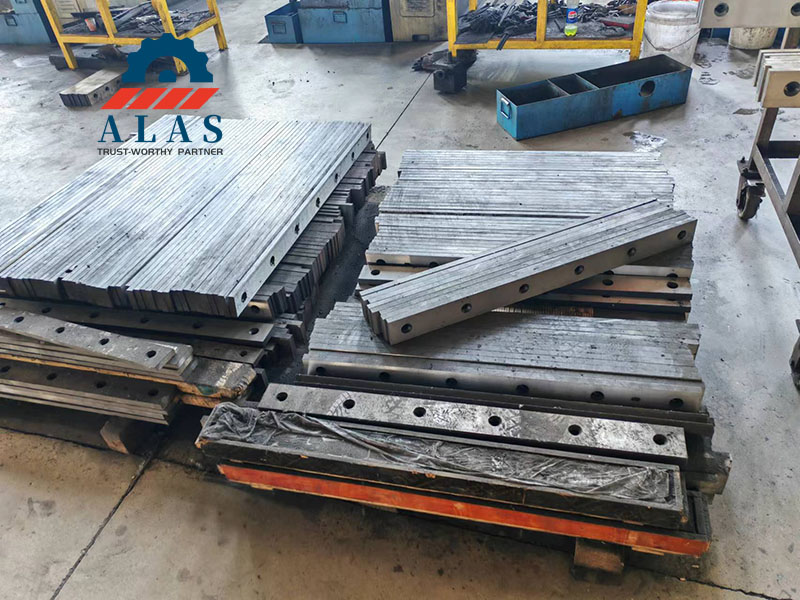 Inventario a granel de cuchillas de guillotina industriales apiladas sobre paletas de madera en un almac&eacute;n de f&aacute;brica