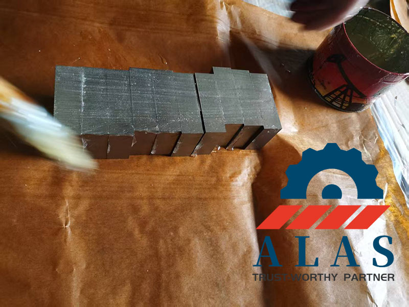 Trabajadores que aplican aceite protector antioxidante y envuelven cuchillas de corte de barras de refuerzo industriales terminadas en papel kraft profesional a prueba de humedad