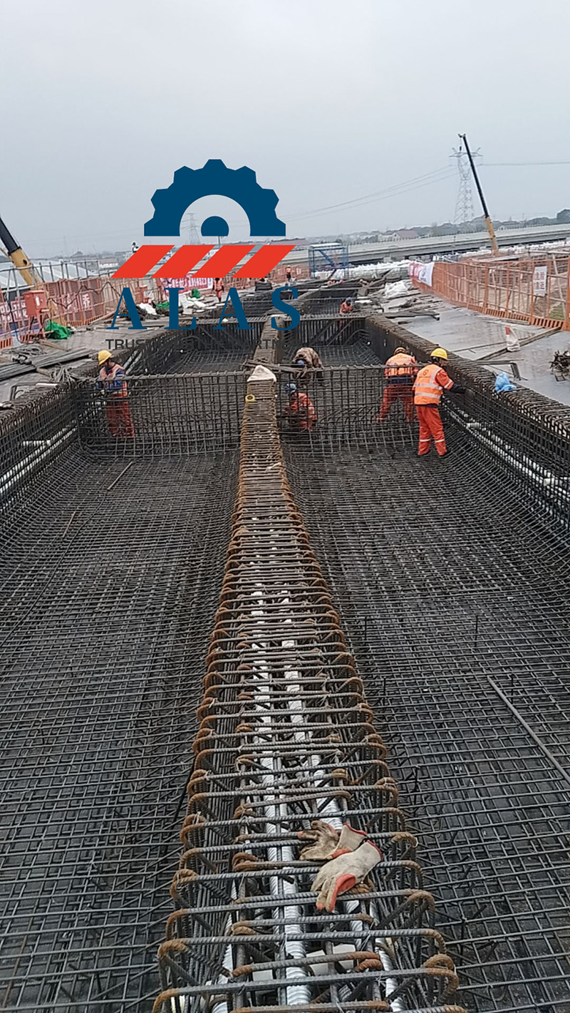 Un sitio de construcci&oacute;n de puentes de infraestructura a gran escala con trabajadores instalando un enorme dise&ntilde;o de esqueleto de refuerzo de barras de refuerzo de alta resistencia y servicio pesado