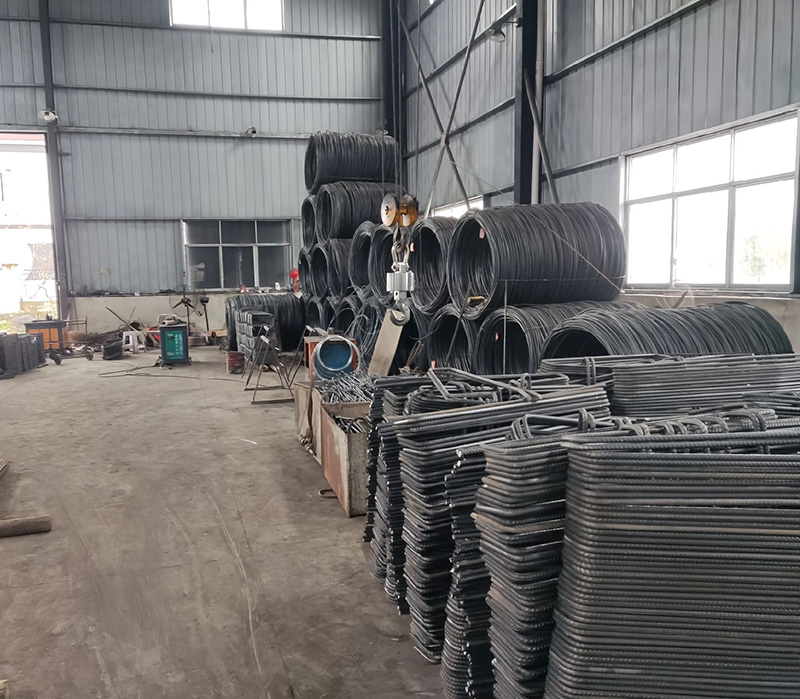 Componentes de barras de acero dobladas y bobinas de alambr&oacute;n dentro de un taller de fabricaci&oacute;n de refuerzo industrial