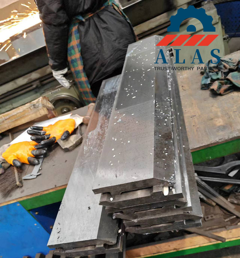 Troqueles de punzonado de plegadora de precisi&oacute;n apilados en una mesa de trabajo durante el proceso final de rectificado y fabricaci&oacute;n en la f&aacute;brica de ALAS