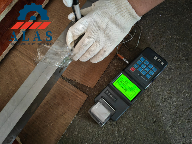 Inspecci&oacute;n de calidad de una hoja de cizalla para corte de metales industrial sometida a pruebas de dureza para verificar 55,6 HRC